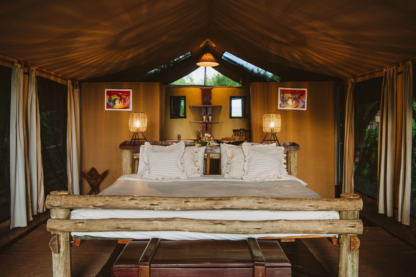 Bed met houtwerk verlicht door lantaarnlicht in een tent op Katavi Wildlife Camp